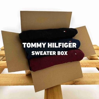Tommy Hilfiger Sweater Box met drie opgevouwen truien in een kartonnen doos op een houten pallet, aangeboden door Vintagebulk.